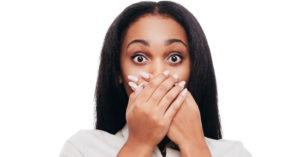 A black woman with bad teeth covering her mouth with her hands.